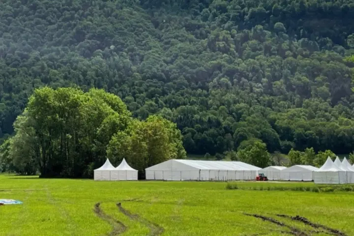 Tentes blanches alignées sur le terrain des Mondiaux de parapente 2023