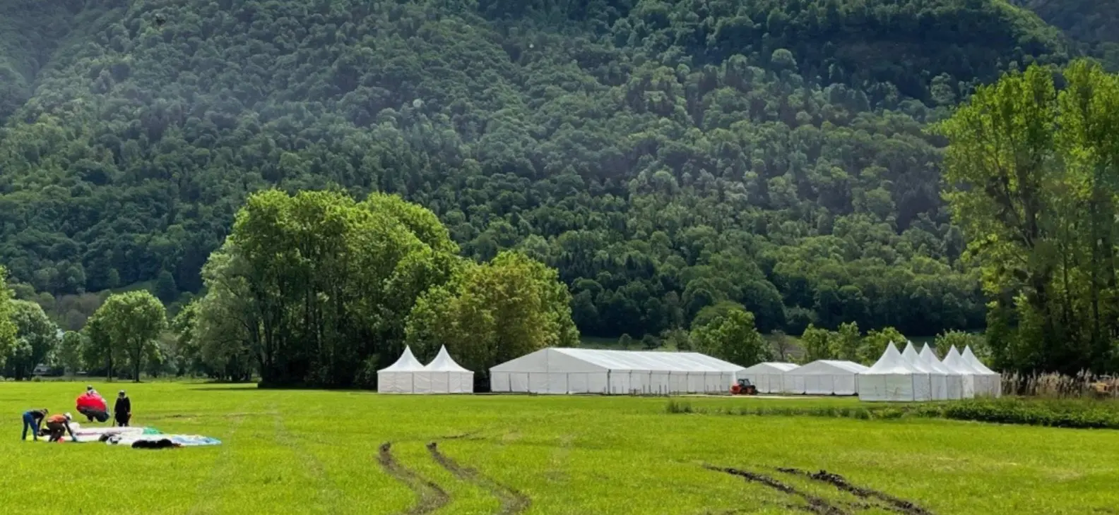 Tentes blanches alignées sur le terrain des Mondiaux de parapente 2023