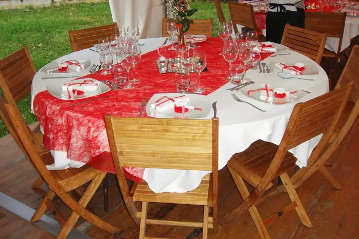 Table ronde nappée de rouge entourée de chaises en teck