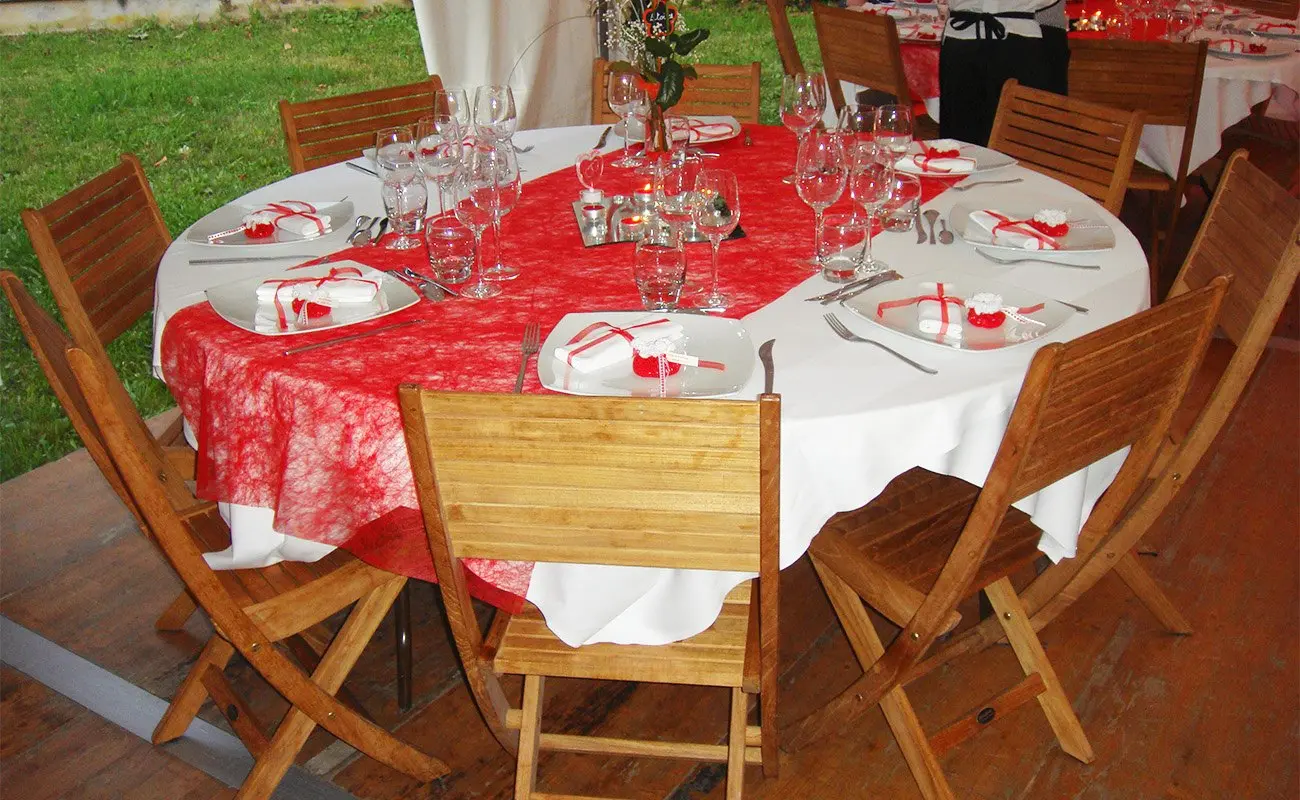 Table ronde nappée de rouge entourée de chaises en teck