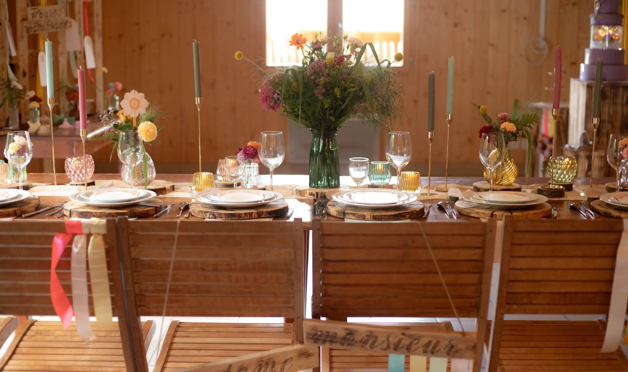 Table de mariage dressée dans un chalet : assiettes, verres, bougies et bouquets